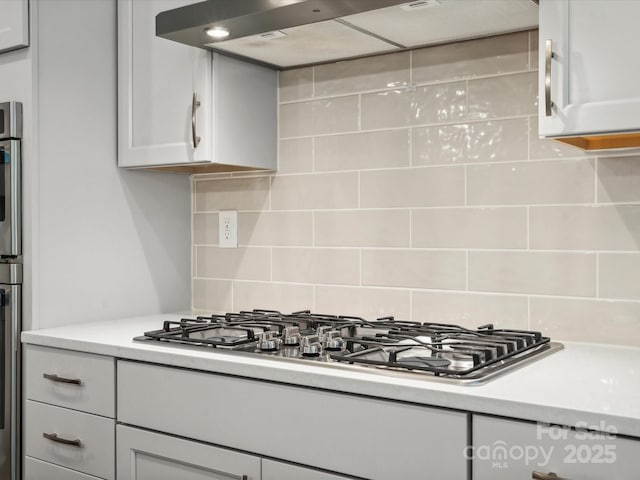 kitchen with wall chimney range hood, backsplash, and stainless steel gas stovetop