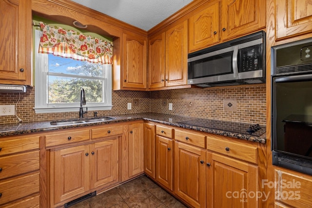 kitchen with black appliances, dark stone countertops, sink, and tasteful backsplash