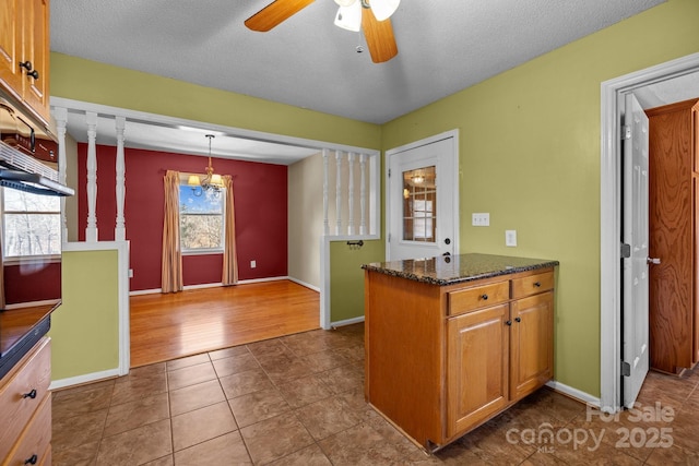 kitchen with tile patterned floors, ceiling fan, a textured ceiling, decorative light fixtures, and kitchen peninsula