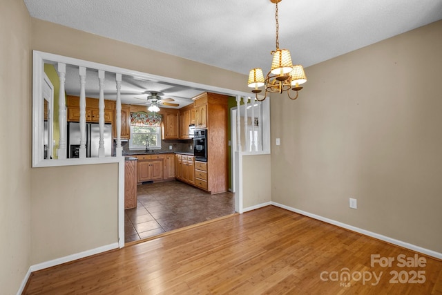 kitchen with stainless steel refrigerator with ice dispenser, backsplash, dark wood-type flooring, decorative light fixtures, and black oven