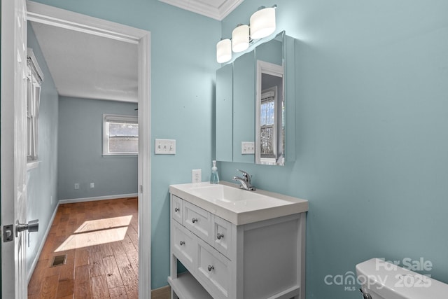 bathroom featuring crown molding, hardwood / wood-style floors, vanity, and toilet