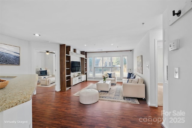 living room featuring ceiling fan and dark wood-type flooring