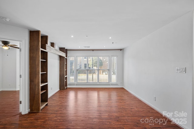 unfurnished living room with built in shelves, ceiling fan, and dark wood-type flooring