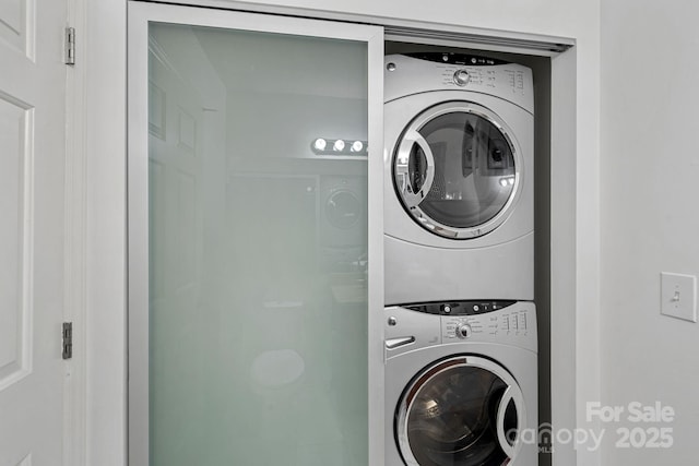 clothes washing area featuring stacked washer and clothes dryer