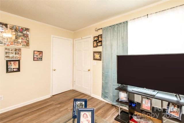 living room featuring baseboards, wood finished floors, and ornamental molding