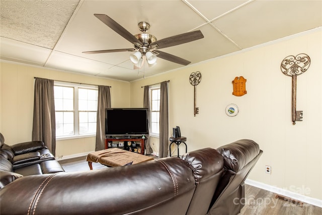 living room with visible vents, crown molding, baseboards, wood finished floors, and a ceiling fan