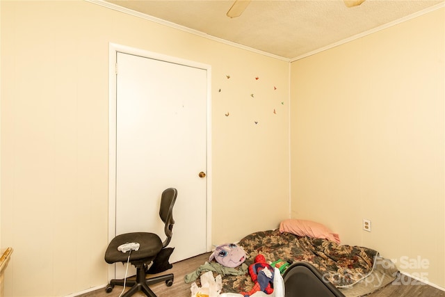 bedroom with crown molding, wood finished floors, and a textured ceiling