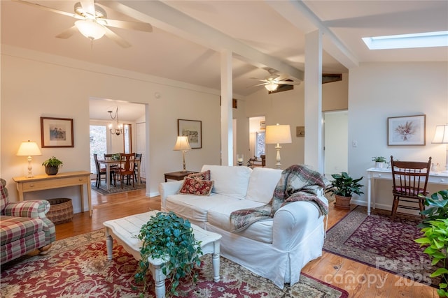 living room with ceiling fan, vaulted ceiling with skylight, and light wood-type flooring