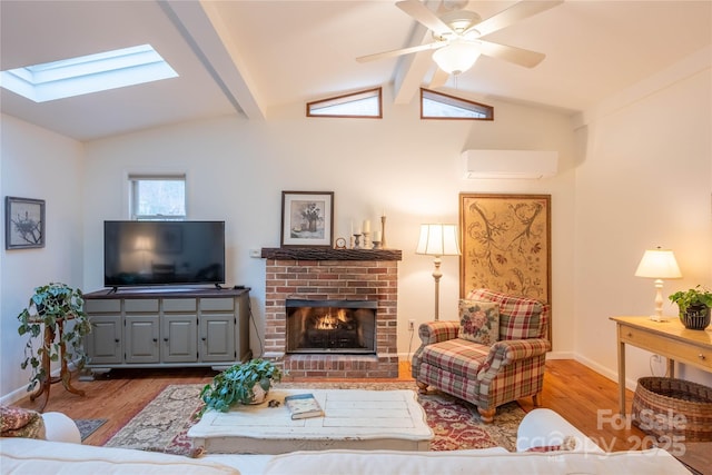 living room with a brick fireplace, an AC wall unit, vaulted ceiling with skylight, and light hardwood / wood-style flooring