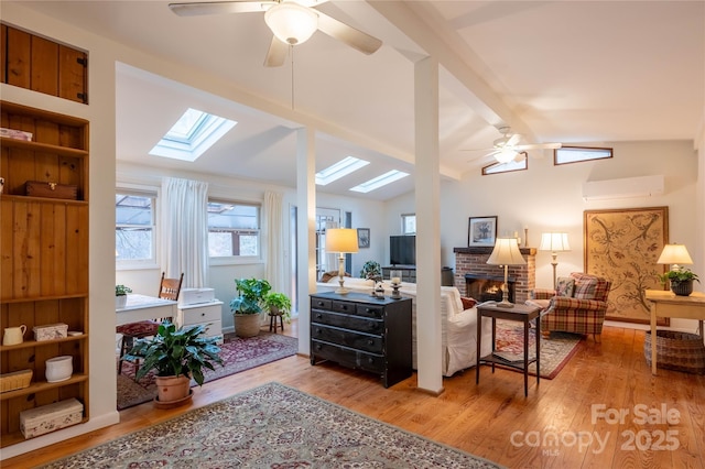 living room featuring a fireplace, a wall mounted AC, ceiling fan, light hardwood / wood-style floors, and built in shelves