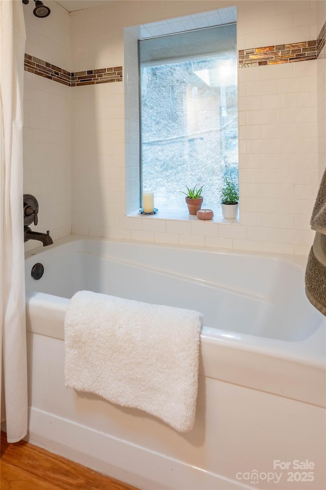 bathroom with hardwood / wood-style flooring and shower / bath combo with shower curtain