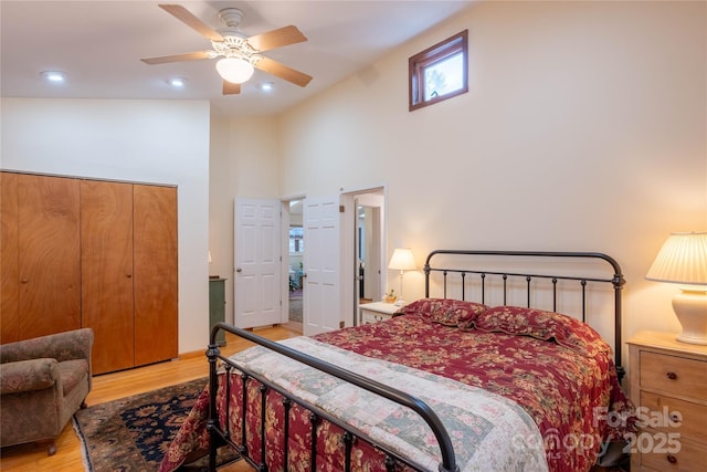 bedroom with a closet, ceiling fan, high vaulted ceiling, and light hardwood / wood-style flooring