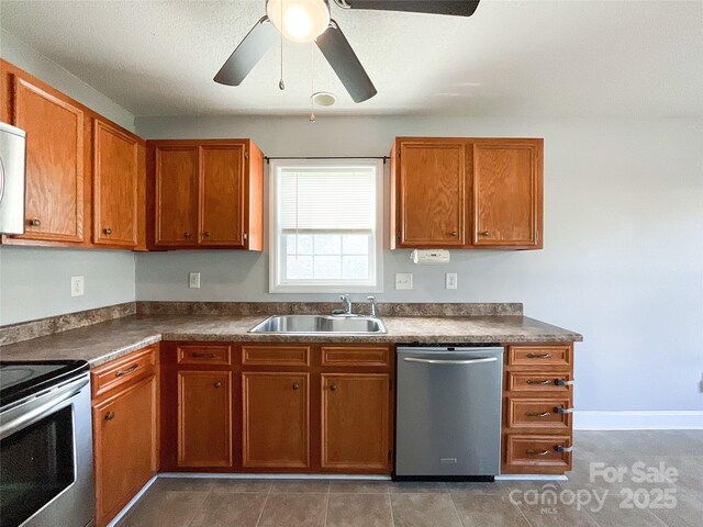 kitchen with sink, stainless steel appliances, dark tile patterned floors, and ceiling fan