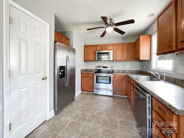 kitchen with sink, a textured ceiling, ceiling fan, light tile patterned floors, and appliances with stainless steel finishes