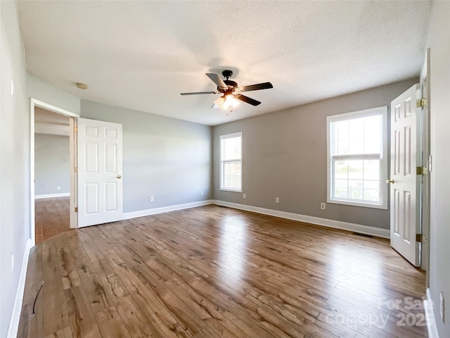 empty room featuring ceiling fan, light wood-type flooring, and a textured ceiling