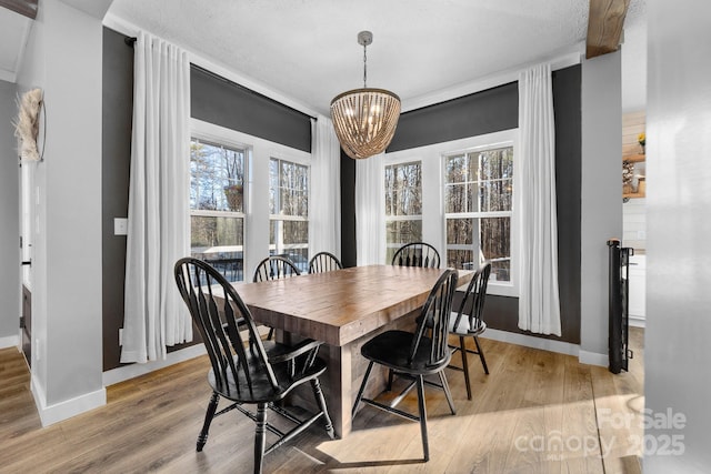 dining space with a textured ceiling, light hardwood / wood-style floors, and a chandelier