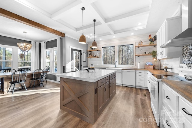 kitchen with white appliances, white cabinets, wall chimney range hood, and pendant lighting