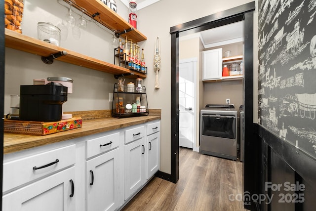 washroom featuring bar, separate washer and dryer, wood-type flooring, and ornamental molding