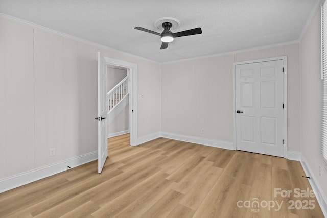 spare room with crown molding, ceiling fan, a textured ceiling, and light wood-type flooring