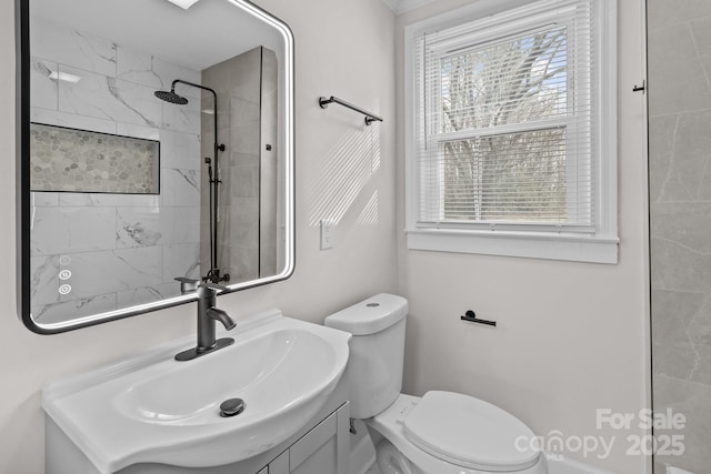 bathroom featuring a tile shower, vanity, and toilet