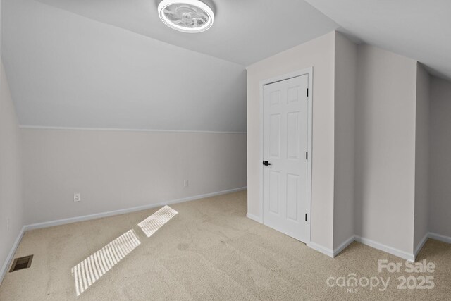 additional living space featuring light colored carpet and vaulted ceiling