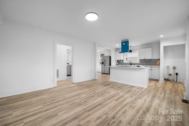 kitchen with backsplash, stainless steel fridge with ice dispenser, light hardwood / wood-style flooring, and white cabinets