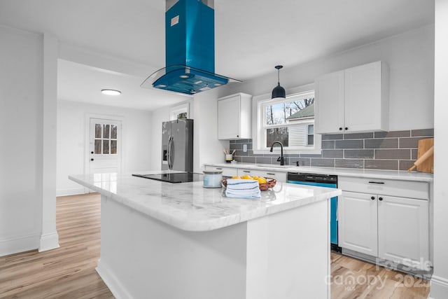 kitchen featuring a center island, exhaust hood, white cabinets, sink, and stainless steel fridge