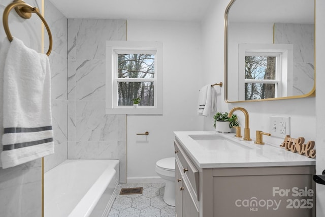 bathroom with vanity, a bathtub, toilet, and plenty of natural light