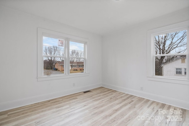 spare room featuring light hardwood / wood-style flooring and a healthy amount of sunlight