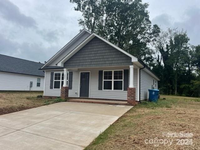 view of front of home with covered porch and a front lawn