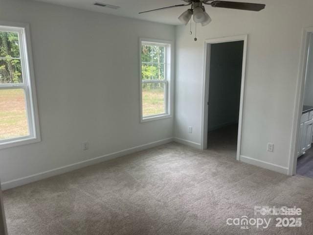 unfurnished bedroom featuring ceiling fan, a spacious closet, carpet, and multiple windows