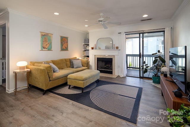 living room with hardwood / wood-style flooring, crown molding, a premium fireplace, and ceiling fan