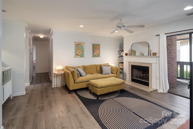 living room with wood-type flooring, ornamental molding, and ceiling fan