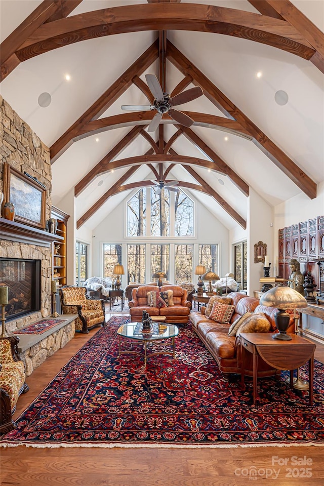 living room with hardwood / wood-style floors, high vaulted ceiling, beamed ceiling, and a fireplace