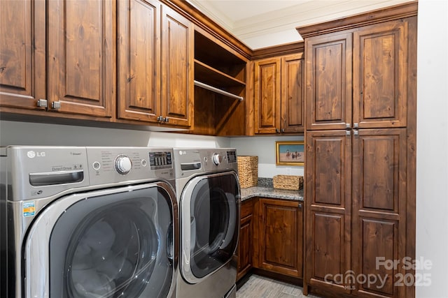 laundry room with washing machine and clothes dryer, crown molding, and cabinets