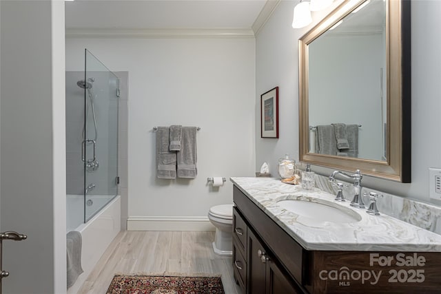 full bathroom featuring toilet, hardwood / wood-style flooring, bath / shower combo with glass door, ornamental molding, and vanity