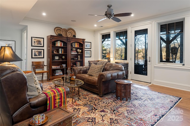 living room with light hardwood / wood-style floors, ceiling fan, and crown molding