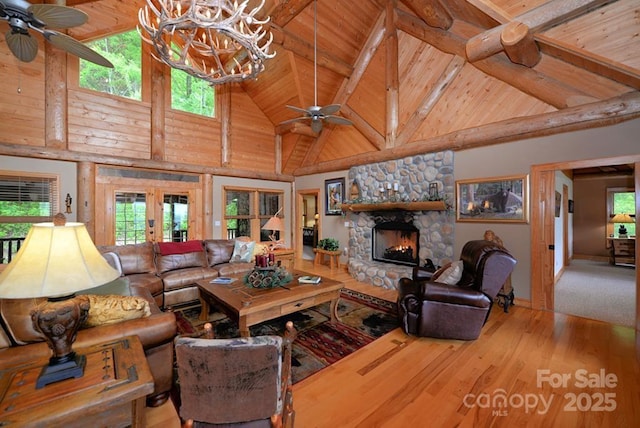 living room featuring ceiling fan, wooden ceiling, a fireplace, and high vaulted ceiling