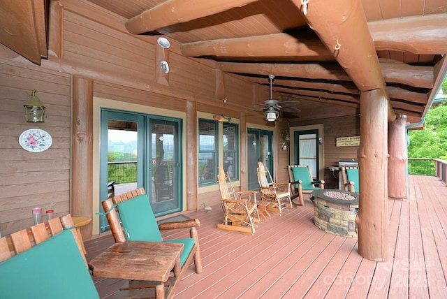 deck featuring covered porch, ceiling fan, and an outdoor fire pit