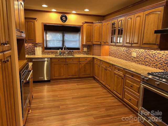 kitchen with decorative backsplash, appliances with stainless steel finishes, light stone counters, and sink