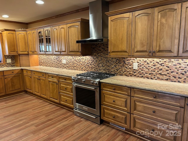 kitchen with wall chimney exhaust hood, decorative backsplash, high end stove, and ornamental molding