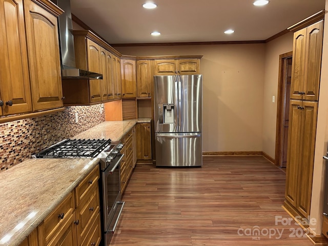 kitchen with decorative backsplash, appliances with stainless steel finishes, dark hardwood / wood-style flooring, light stone countertops, and wall chimney exhaust hood