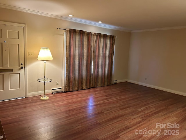 spare room featuring hardwood / wood-style flooring, ornamental molding, and a baseboard heating unit