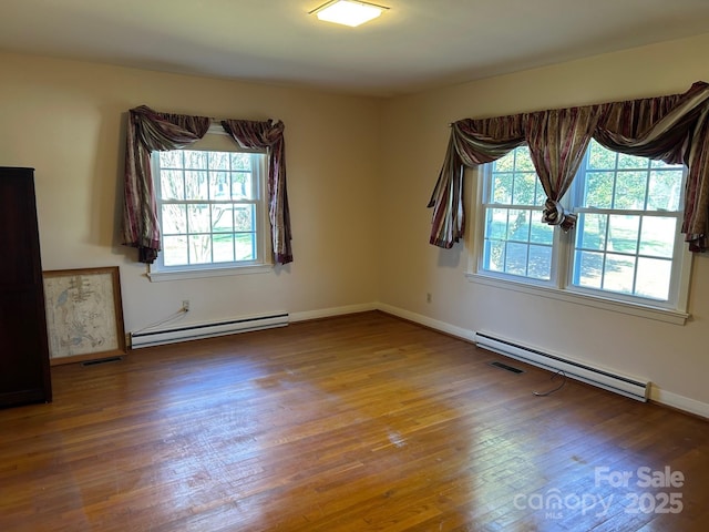 unfurnished room with hardwood / wood-style flooring and baseboard heating