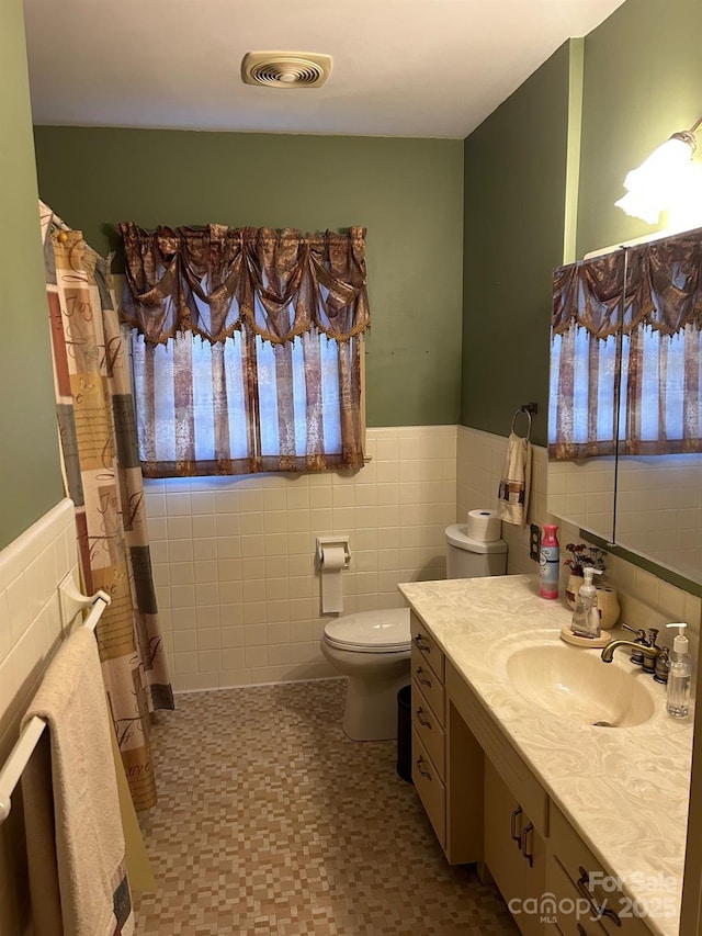 bathroom with a healthy amount of sunlight, tile walls, and toilet