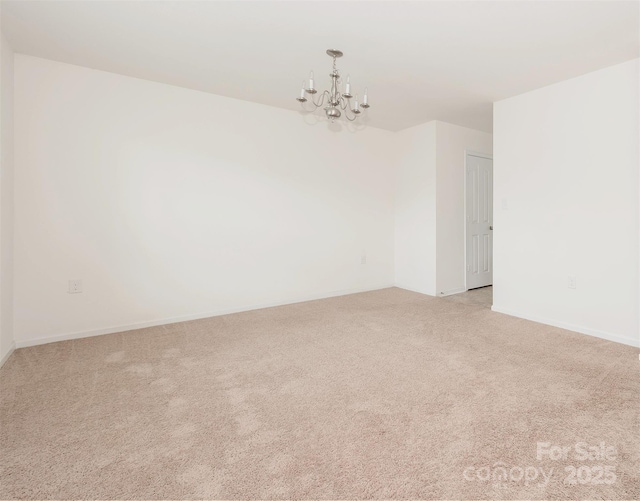 empty room featuring an inviting chandelier and light colored carpet