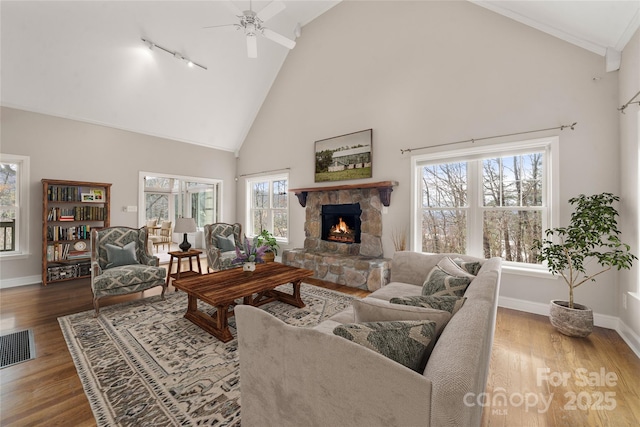 living room featuring a fireplace, wood finished floors, a ceiling fan, visible vents, and baseboards