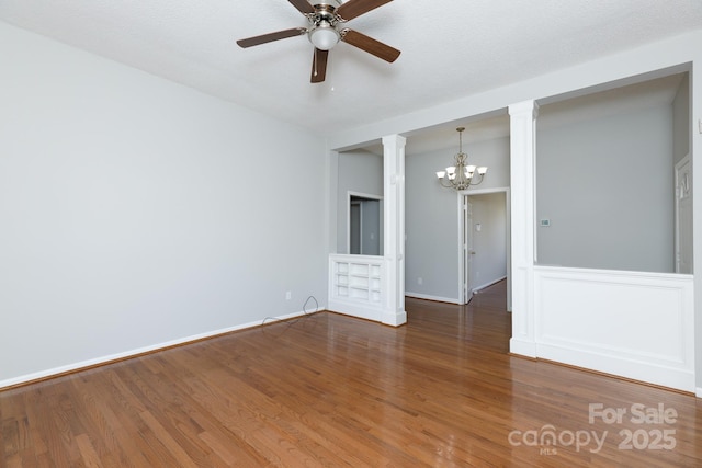 spare room featuring ceiling fan with notable chandelier, a textured ceiling, and dark hardwood / wood-style flooring