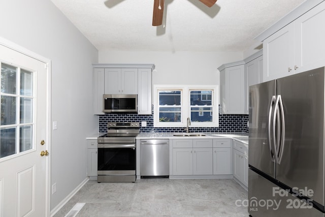 kitchen with appliances with stainless steel finishes, tasteful backsplash, gray cabinetry, and sink