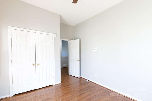 unfurnished bedroom with ceiling fan, wood-type flooring, and a closet